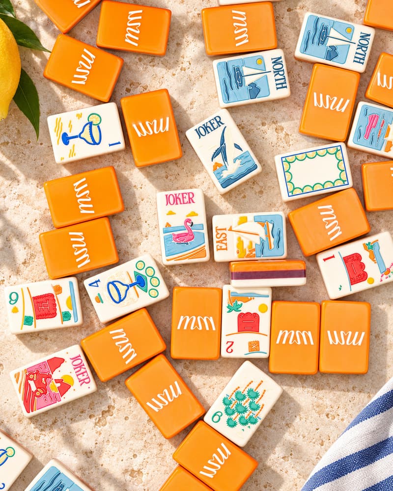 Cabo Set tiles scattered on a sunny stone table, with tangerine backs and beach faces